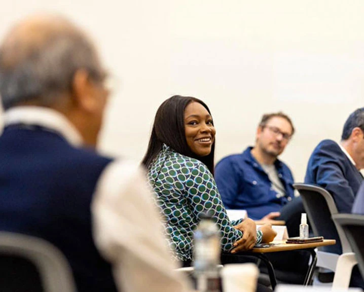 A woman smiles during a group discussion on an Executive Education class.