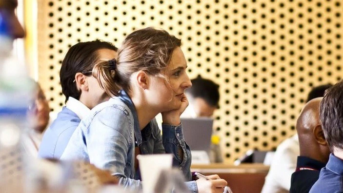 A female student listens attentively during an Executive MBA lecture in a classroom setting.