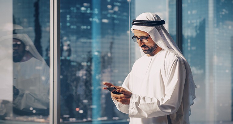 Muslim businessman looking at his phone.