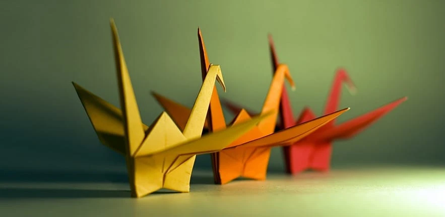 A group of 3 origami birds with the focus on the beak of the yellow bird.