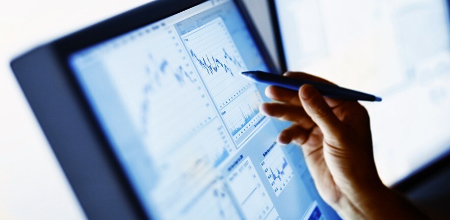 Hand pointing tomarket chart on computer screen.