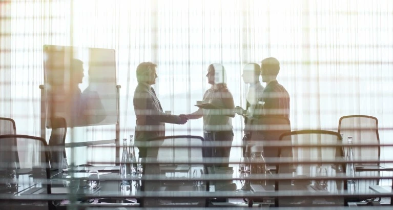 People shaking hands in a meeting room.
