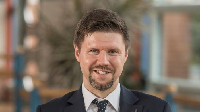 Profile photo of Andrew Breus standing in the Cambridge Judge Business School atrium.