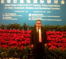 Dr Christos Pitelis stands in front of a conference backdrop in Beijing.