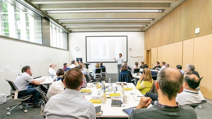 Participants learning from a speaker in a modern classroom setting.