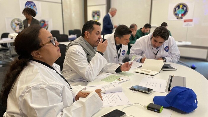 Participants in white lab coats engaged in a collaborative activity at the Emerging Risk Leadership Programme.