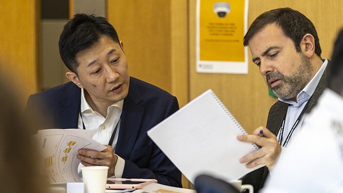 Two businessmen reading notes in a classroom.