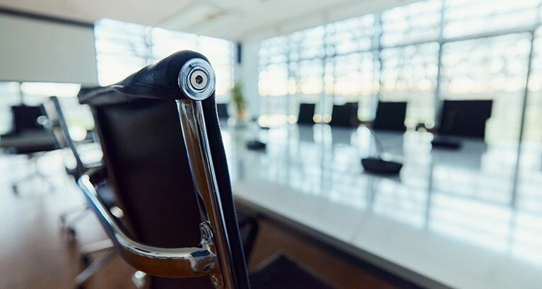 Close up of a chair in empty conference room, not a staff member in sight.