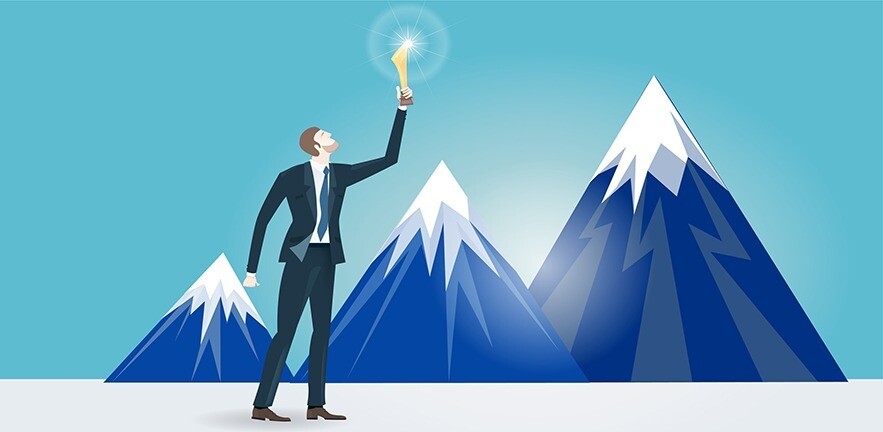 Businessman holding up the golden trophy in front of mountains.