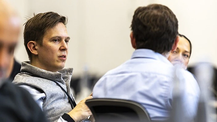 Two men engaged in conversation in a classroom.