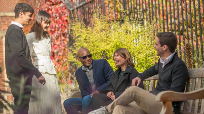MFin students sitting on bench talking and smiling.