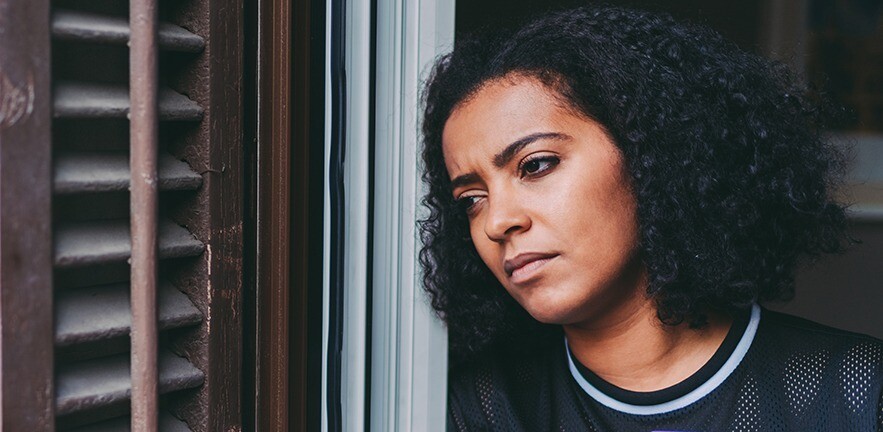 Worried woman looking out of the window.