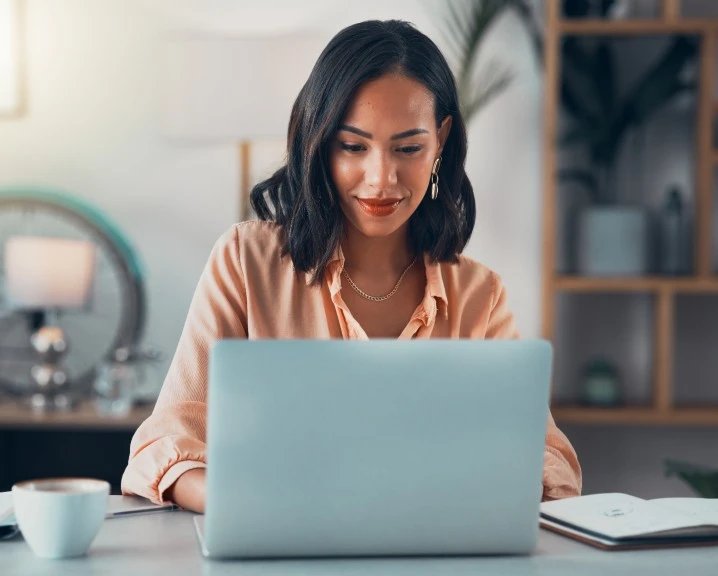 Girl smiling and focused in front of her laptop.