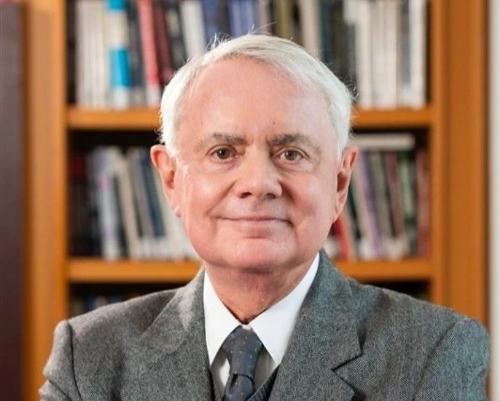 Profile photo of James Bacchus standing in front of a bookcase.