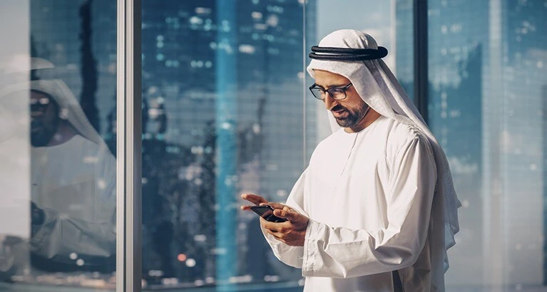 Muslim businessman looking at his phone.