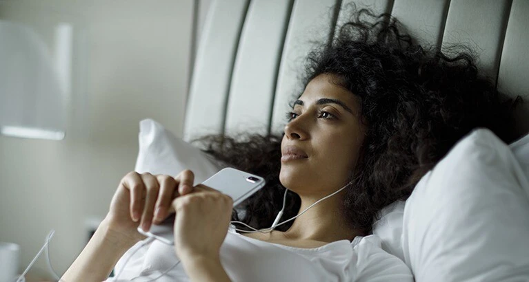 Woman looking thoughtful as she listens to an app on her phone.