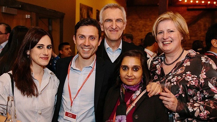 Group of EMBA students smiling together during a social event at Cambridge Judge Business School.
