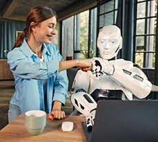 Robot and woman working on laptop in office.