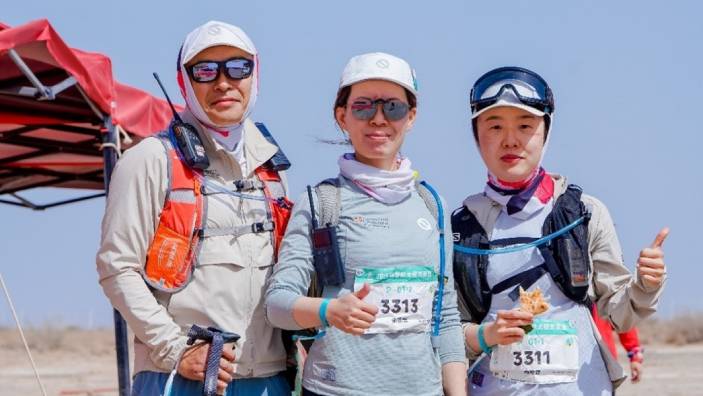 Dr Amy Zhang and Michael Yang holding a trophy at the Will of Nature - Gobi to West 2025 event in hiking gear at the Will of Nature - Gobi to West 2025 event.