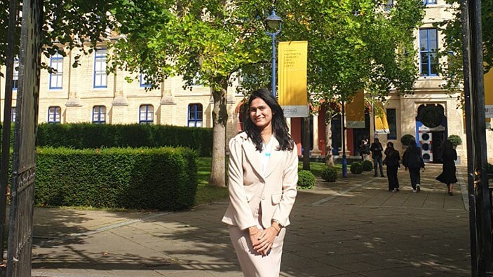 Manisha Chuttoor at the front gates of Cambridge Judge Business School.