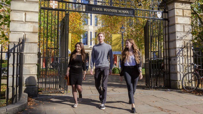 Students walking through the gates of Cambridge Judge Business School.