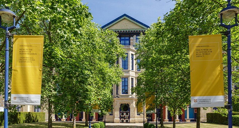 Cambridge Judge Business School in the sunshine with yellow banners.