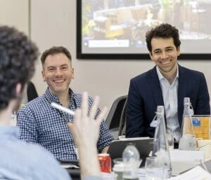 Two men smiling in a classroom.