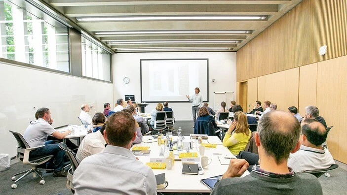Participants learning from a speaker in a modern classroom setting.