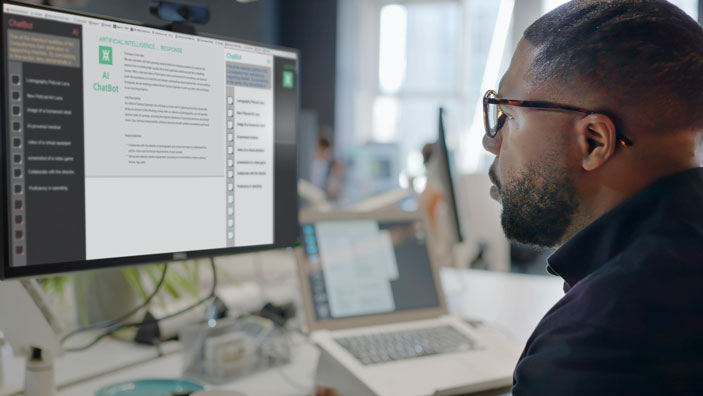 A person using a computer to interact with an AI chatbot in a modern office setting.