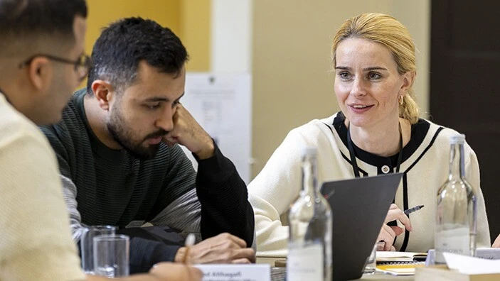 Woman smiling, talking to man in a classroom.