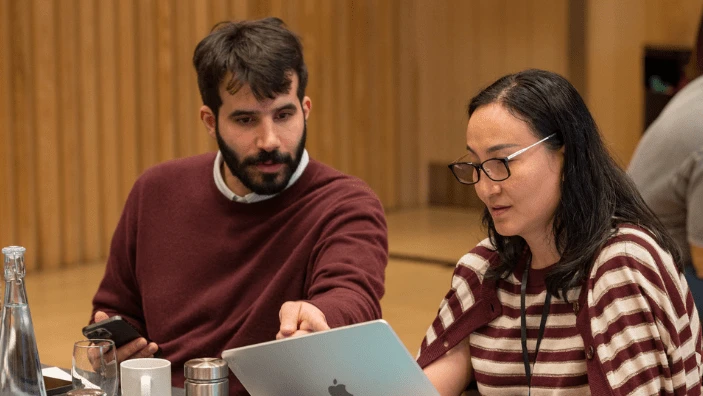 Delegates working on a laptop together in class