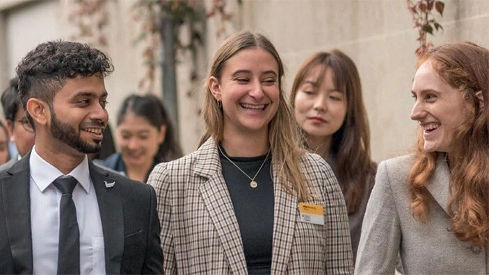 Smiling MBA students walking through Cambridge.