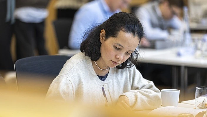 Woman sitting in a classroom, writing.