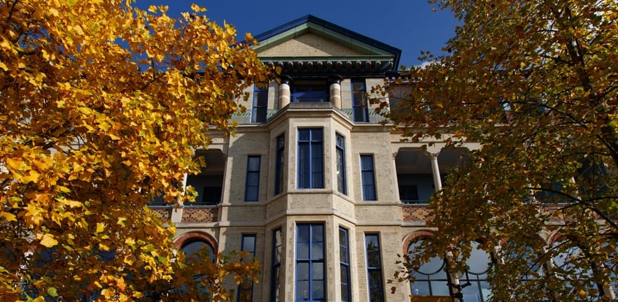 Cambridge Judge Business School exterior with yellow trees.