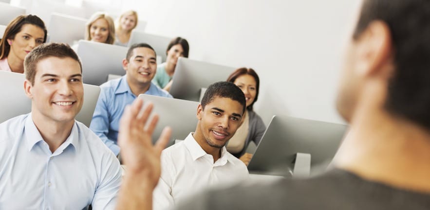 Large group of business people listening to teacher in a computer lab.