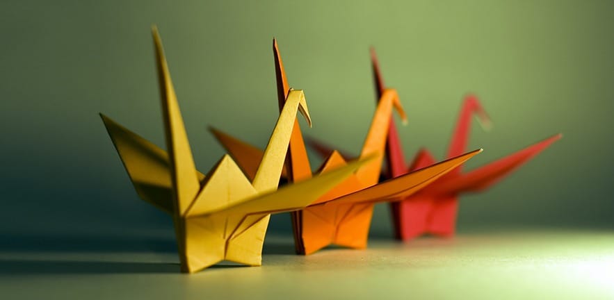 A group of 3 origami birds with the focus on the beak of the yellow bird.