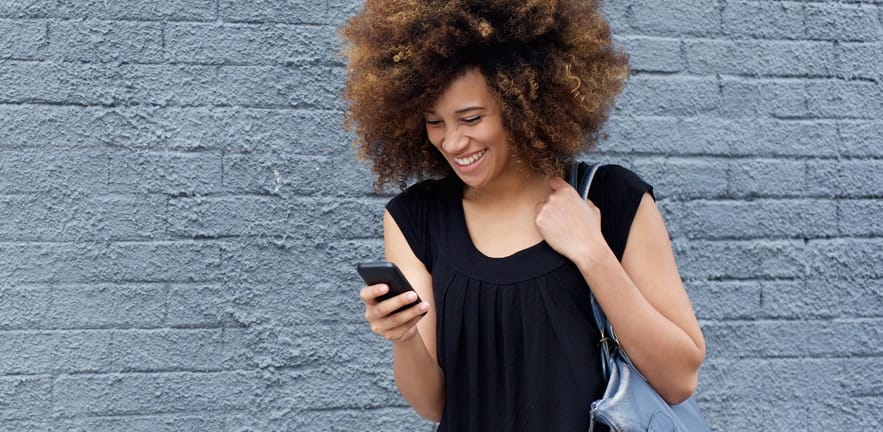 Portrait of smiling woman walking and looking at mobile phone