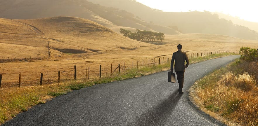 Businessman walking down curving rural road