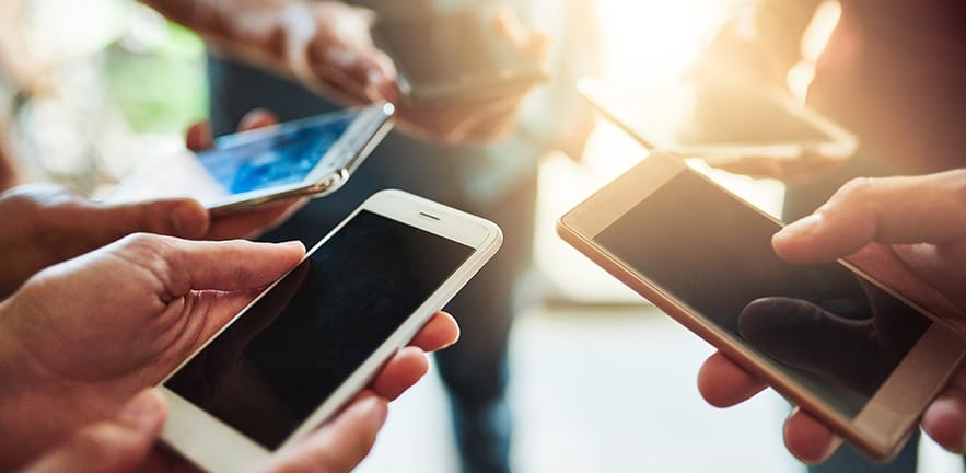 Shot of a group of colleagues using their cellphones together in an office