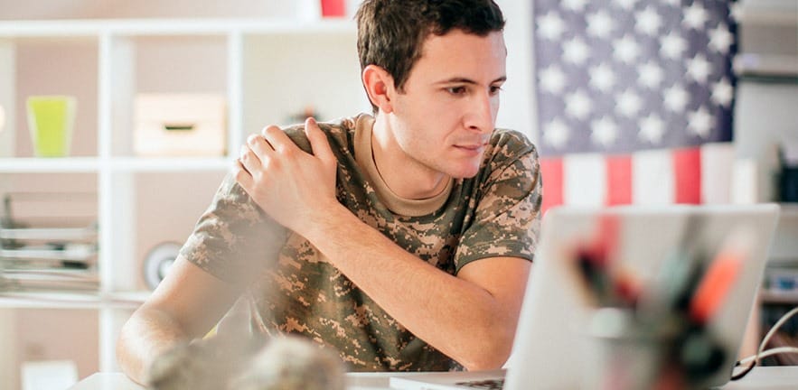 Young soldier using a computer into his office