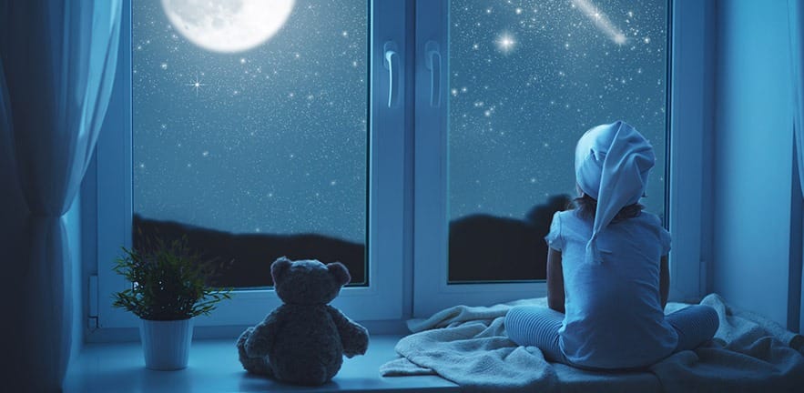 child little girl at the window dreaming and admiring the starry sky at bedtime