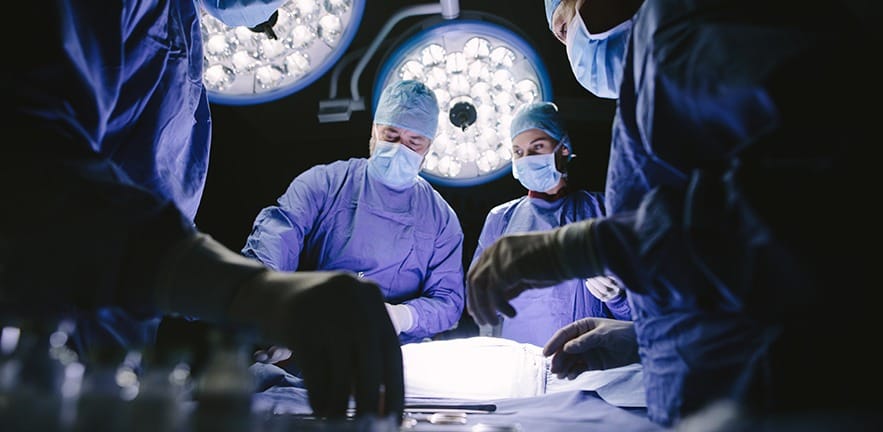 Team of surgeons performing surgery in operation theater. Group of doctors in hospital operating theatre.