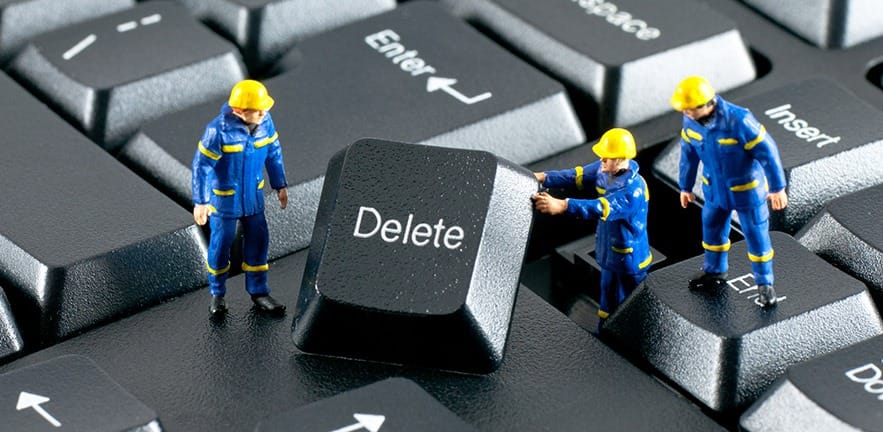 Team of construction workers working with DELETE button on a computer keyboard