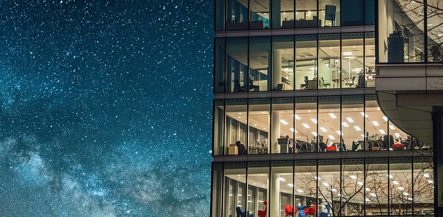 A lit-up skyscraper against a starry blue sky.