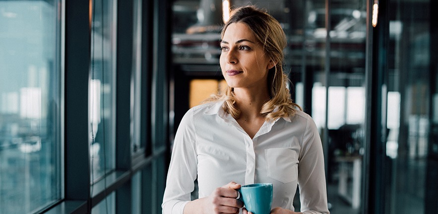 Thoughtful businesswoman looking away with cup of coffee