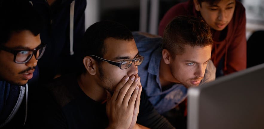 Two men looking in shock at a laptop screen.