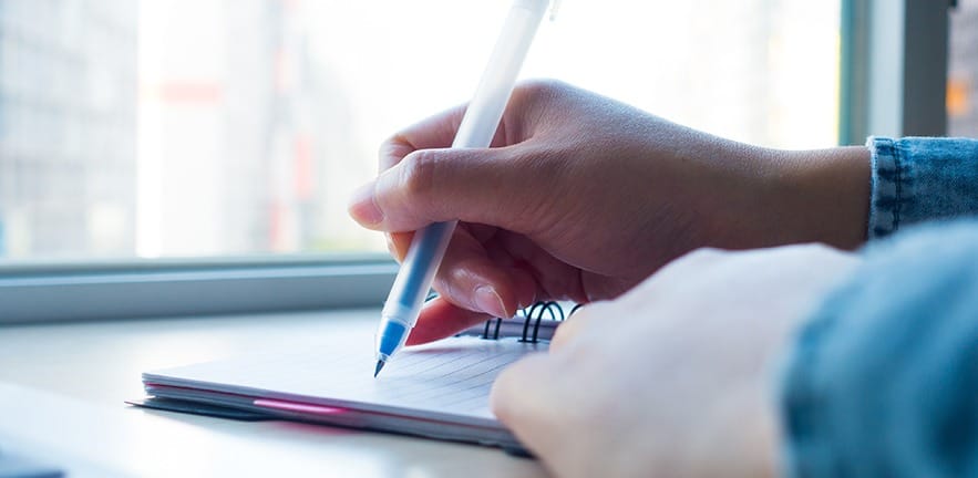 Businesswoman taking ticking off checklist in a notebook in an office.