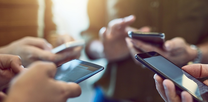 Cropped shot of a group of colleagues using their smart phones in synchronicity