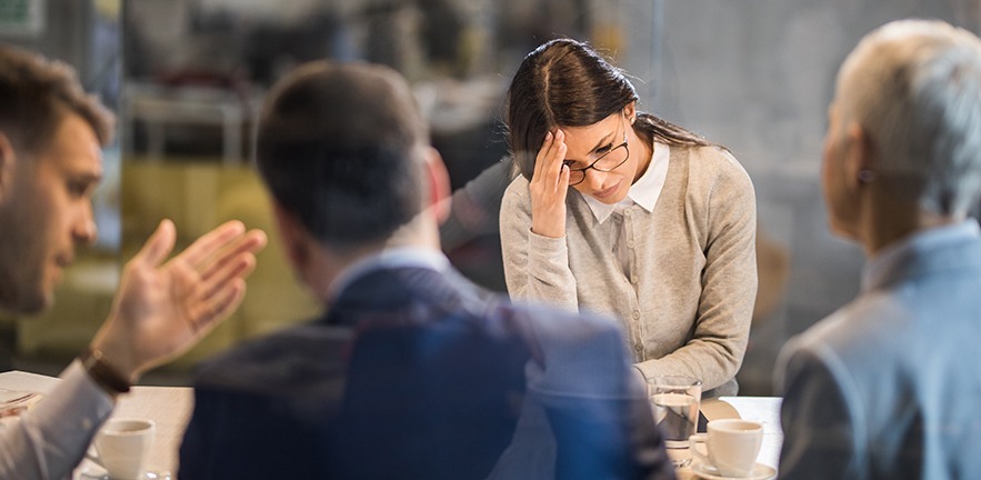 Woman in a work meeting feeling disappointed after failing at work.