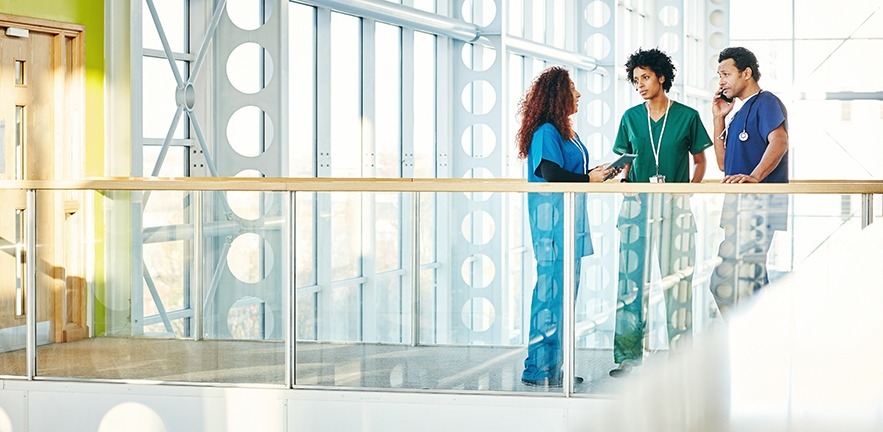 Three medical professionals talking in modern hospital corridor